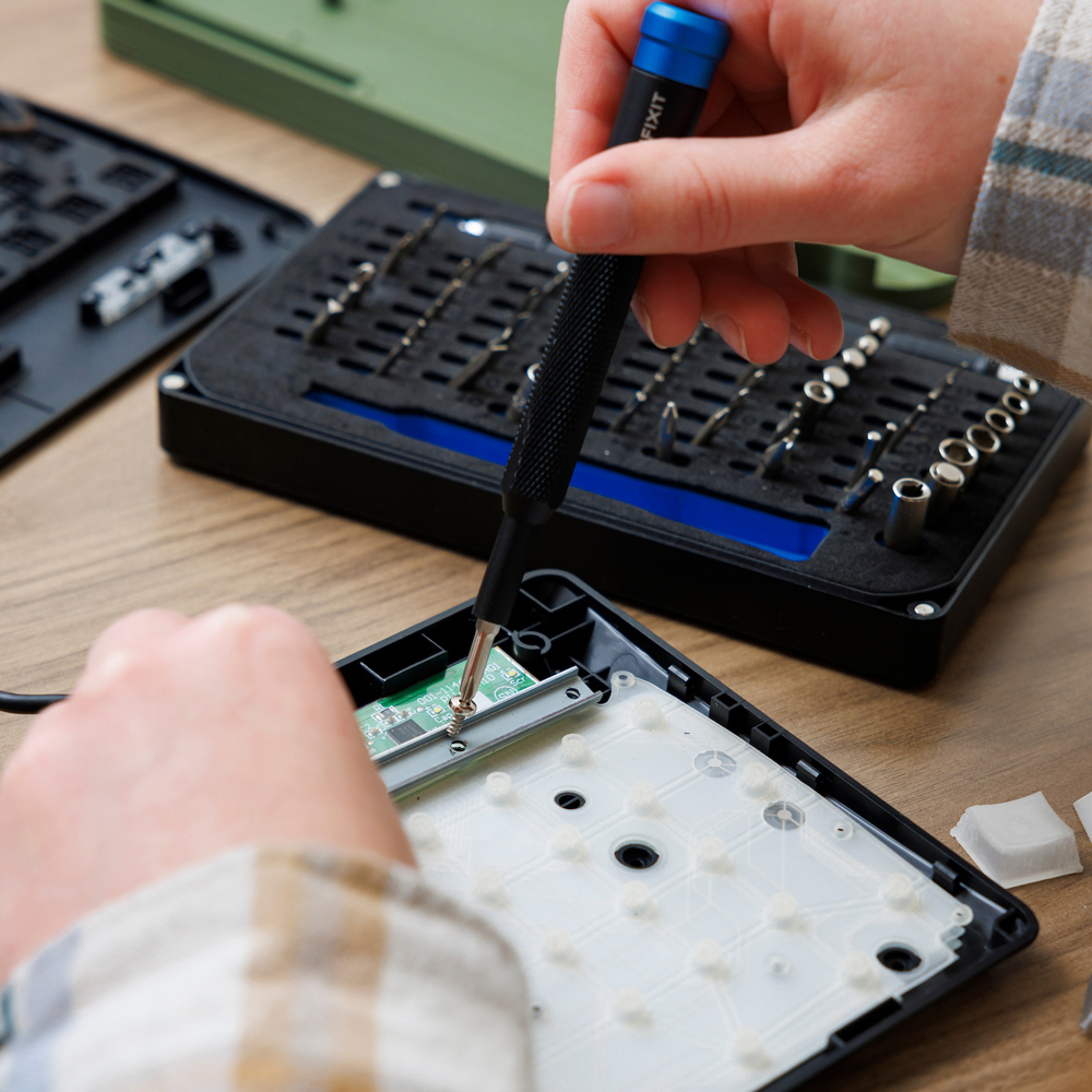 A student uses a screwdriver to attach a component of a membrane keyboard