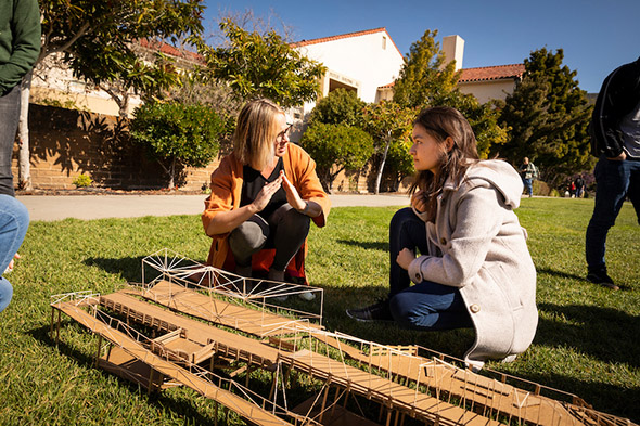 Two students talk next to a model of Harford Pier in Avila Beach.