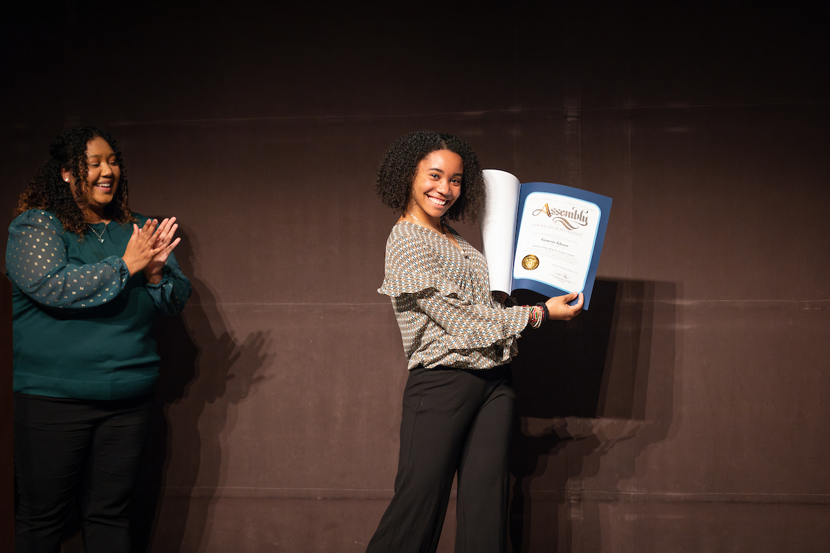 Christina Sholars Ortiz, left, claps as student Genesis Glover smiles and poses with her award certificate.