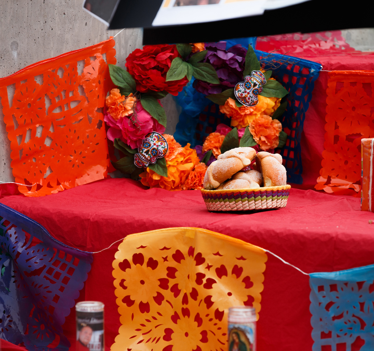An ofrenda decorated with a flower wreath and a basket of pan de muerto.
