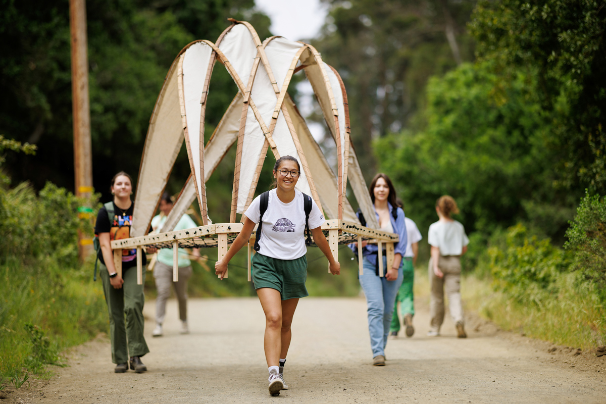 Students carry their designs on the mile-long trail to Poly Canyon.
