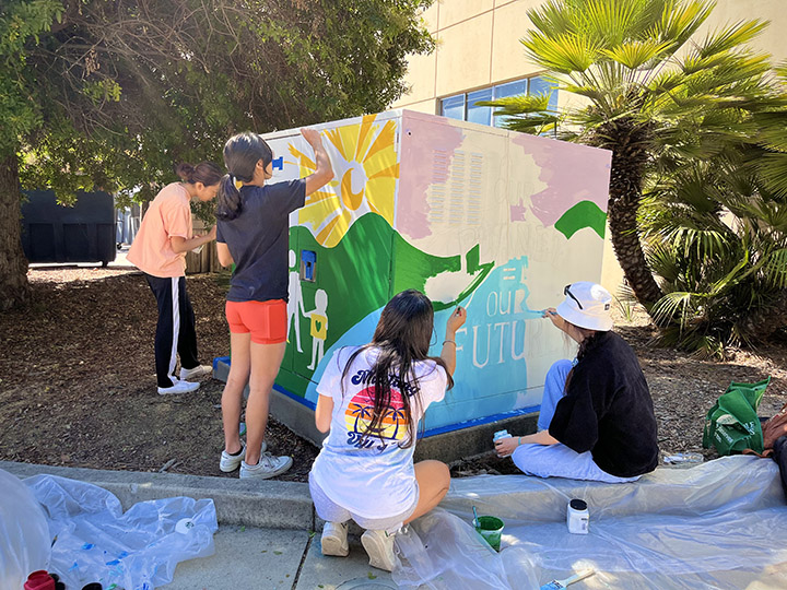 Students paint a utility box on campus