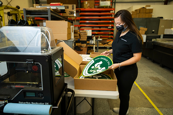 Kinsey Mangan sorts finished signs into boxes for delivery as she and other student employees print signage to be used in buildings on campus during the coronavirus pandemic.