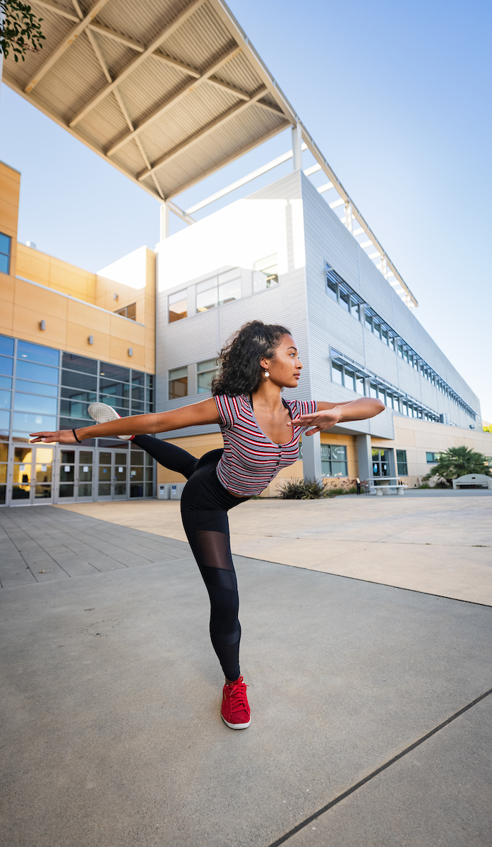 A woman wearing athletic clothes strikes a ballet pose on Cal Poly's campus.