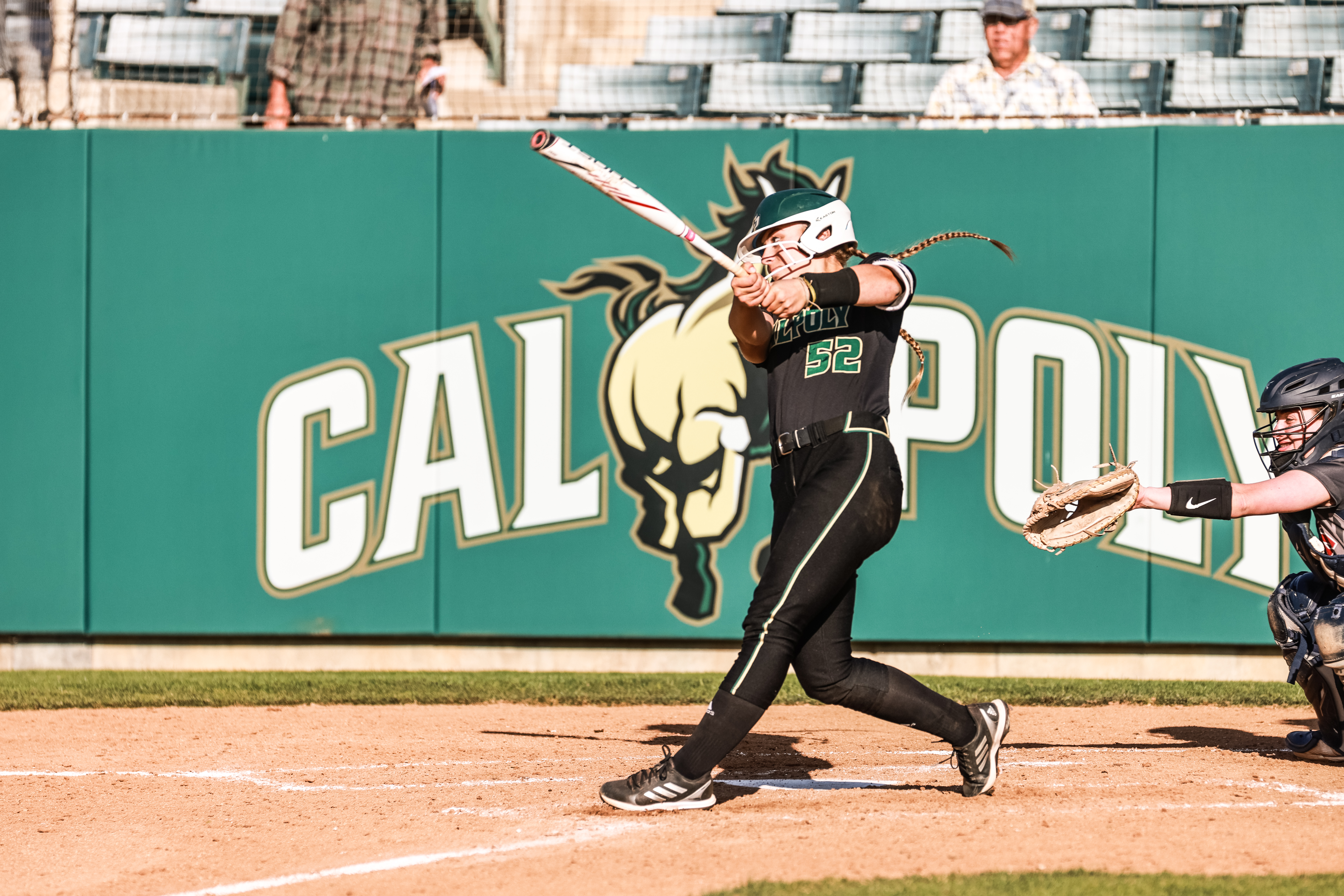 A woman in a black Cal Poly softball uniform bats during a game.