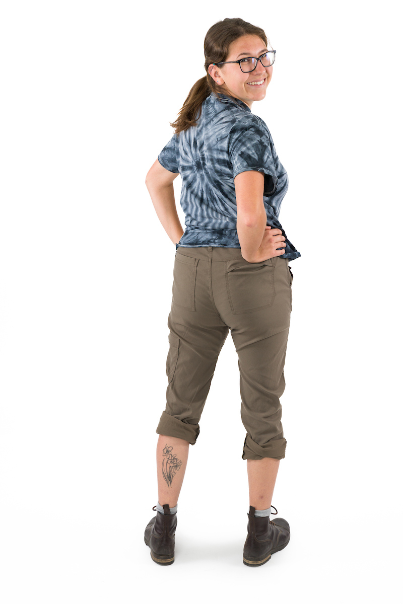 A young woman in rolled up pants shows a tattoo of a daffodil on her left leg