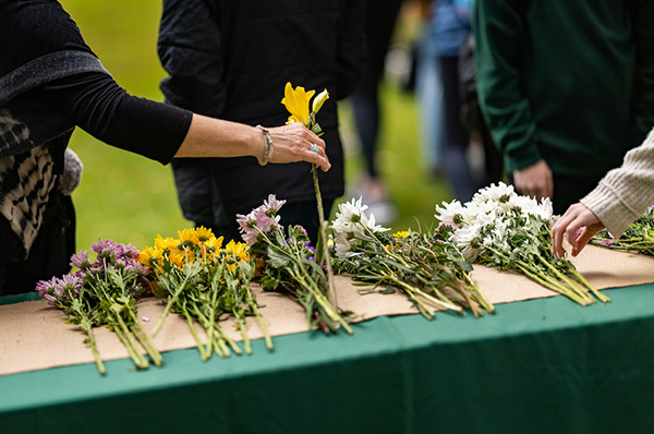 Individuals take flowers at a COVID-19 memorial on O'Neill Green on April 19