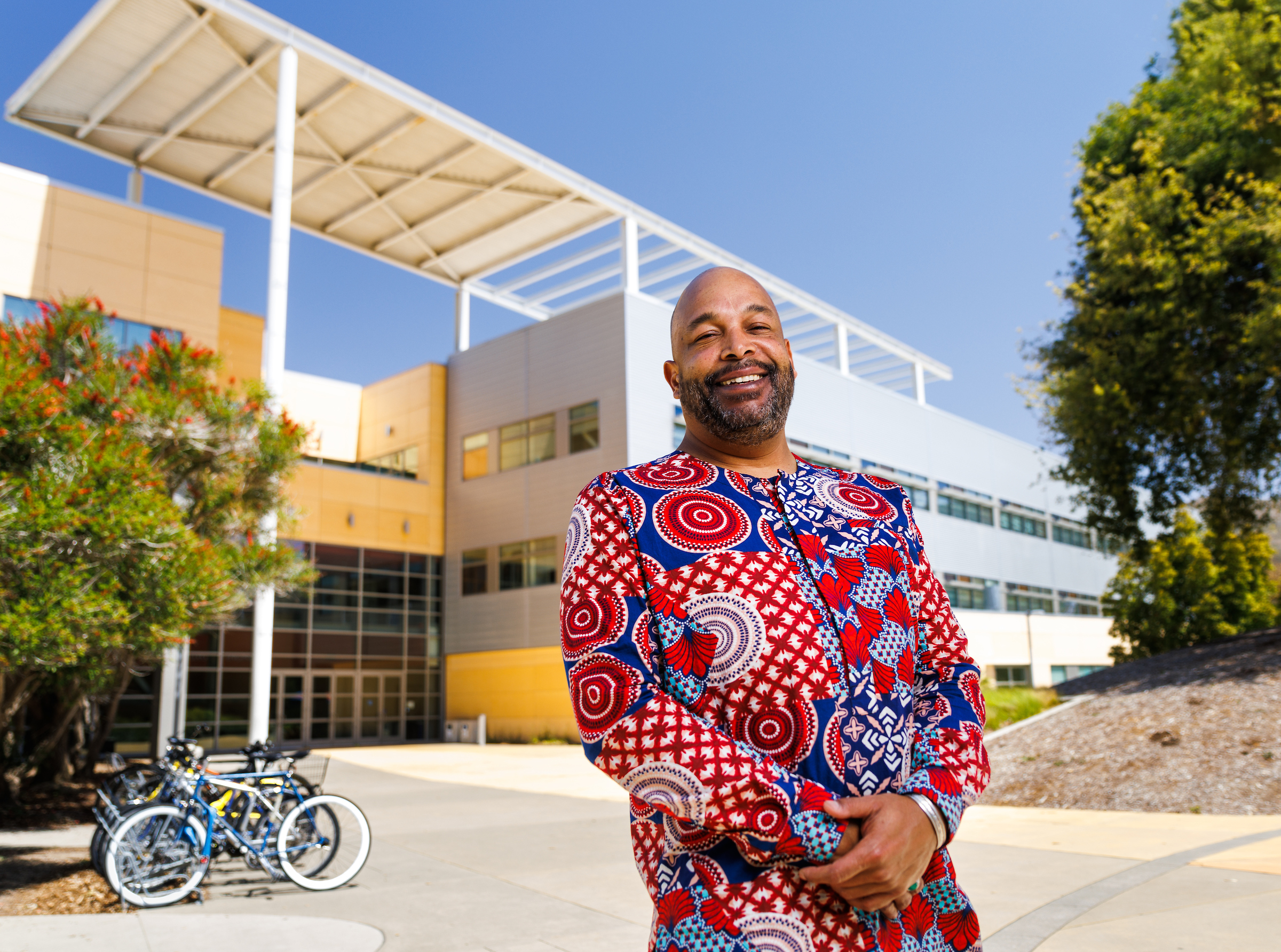 Recent engineering graduate Jon Gausman wears colorful clothing and smiles in a portrait taken on campus.