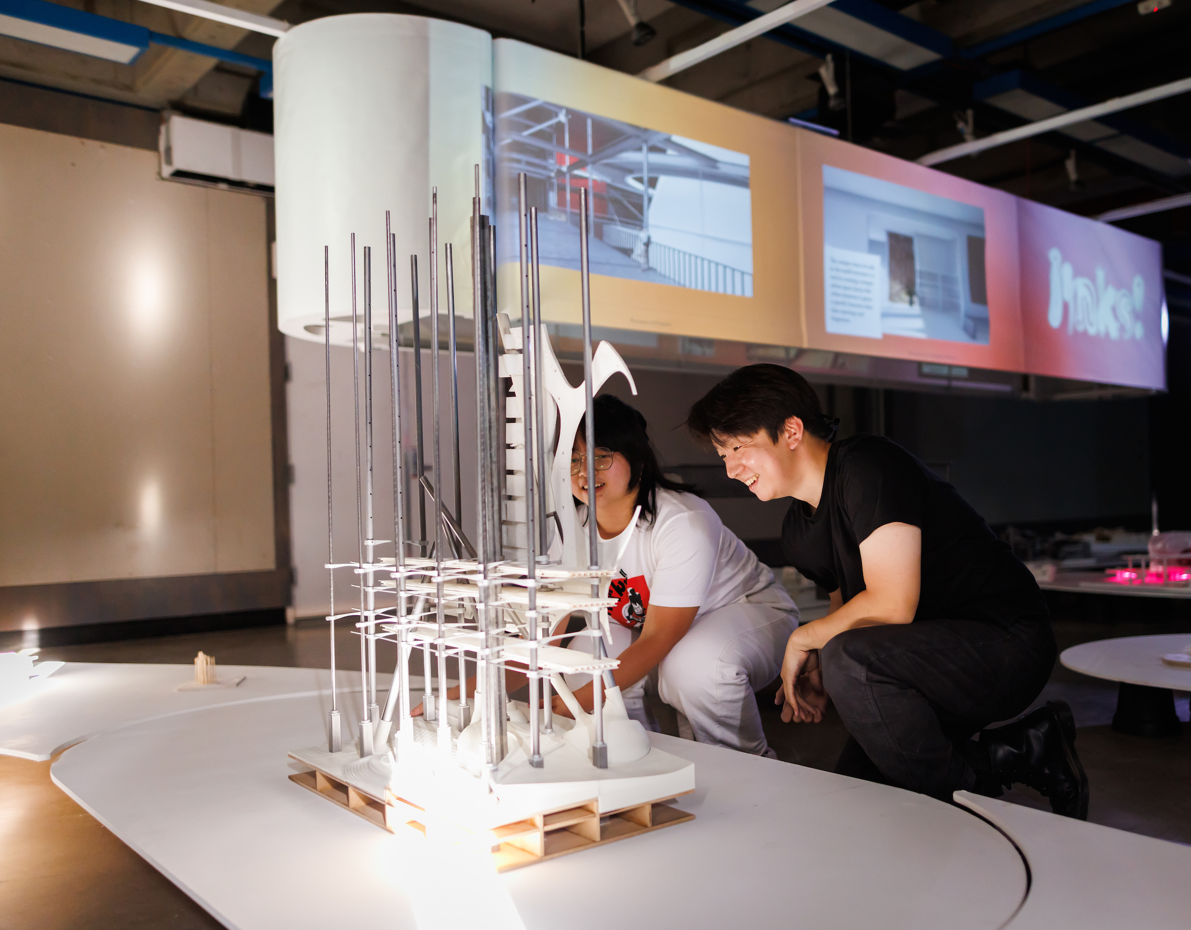 Two architecture students look at an exhibit they constructed. 