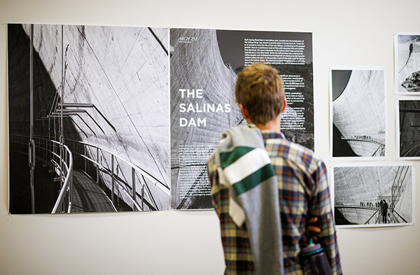 A student looks at photos of the Salinas Dam at an exhibit in the College of Architecture and Environmental Design lobby.