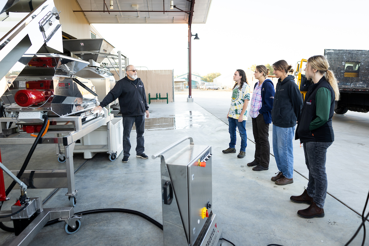 Wine and viticulture students receive instruction on the new destemmer machine.