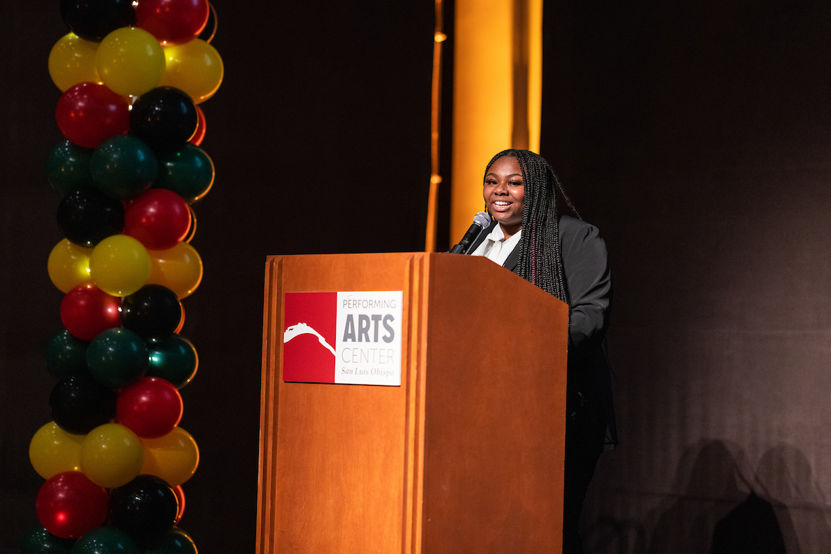 Nailah DuBose gives a speech at a wooden podium at the MLK Jr. Legacy Event.