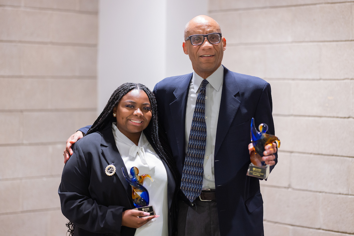 Nailah DuBose, left, poses with Professor Michael Whitt, right, as they hold their awards. Both are wearing navy blazers and white shirts. 