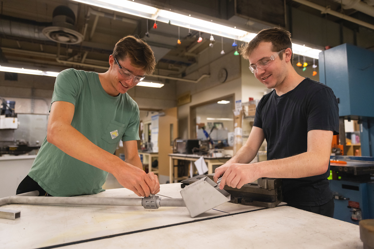 Two students work on a prototype for an extension mechanism handle at a lab at Cal Poly.