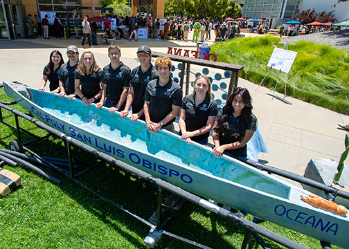 Eight team members gather along the side of their concrete canoeOceana