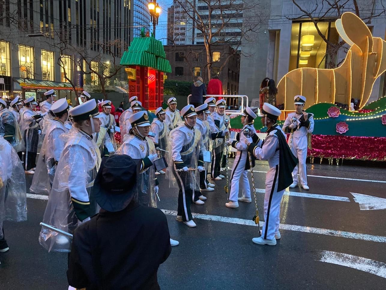 Band members perform while marching down a city street at dusk