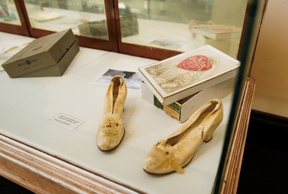 100-year-old wedding shoes and a vintage box with a heart on it sit in a display case.