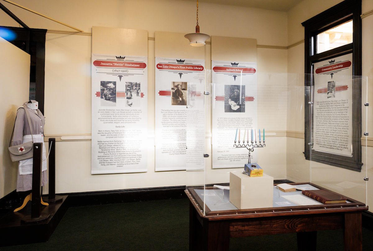 A corner of the historical exhibit shows a vintage nurse's uniform on display, information on posters and a menorah.
