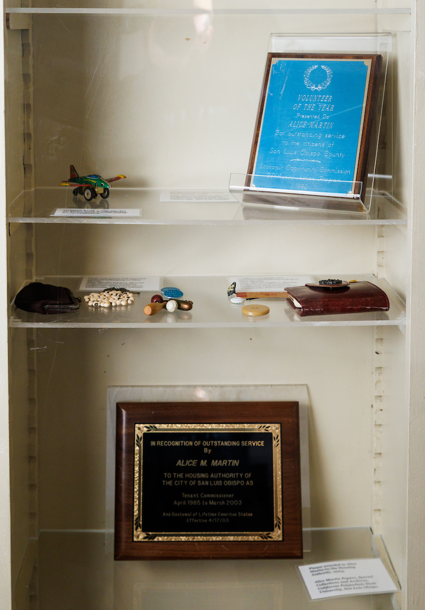 A display case of items that belonged to Alice Martin includes bus tokens, her coin purse and plaques for her volunteer service.