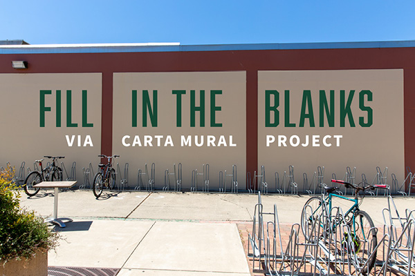 Fill in the blanks Via Carta Mural Project text over photo of the exterior wall of the Food Processing Building