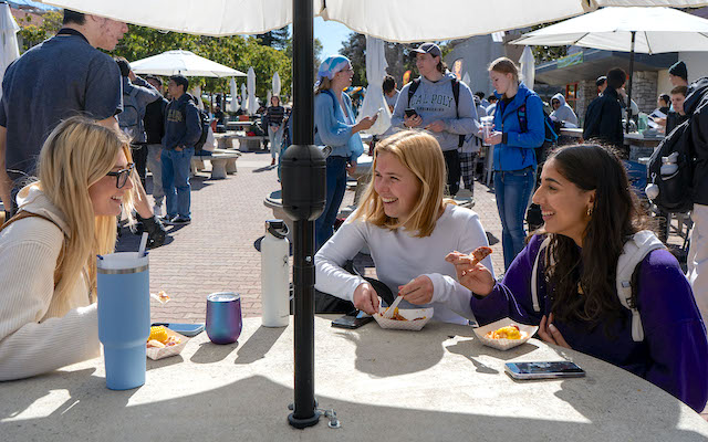 Several students eat at the concrete tables outside Campus Market.