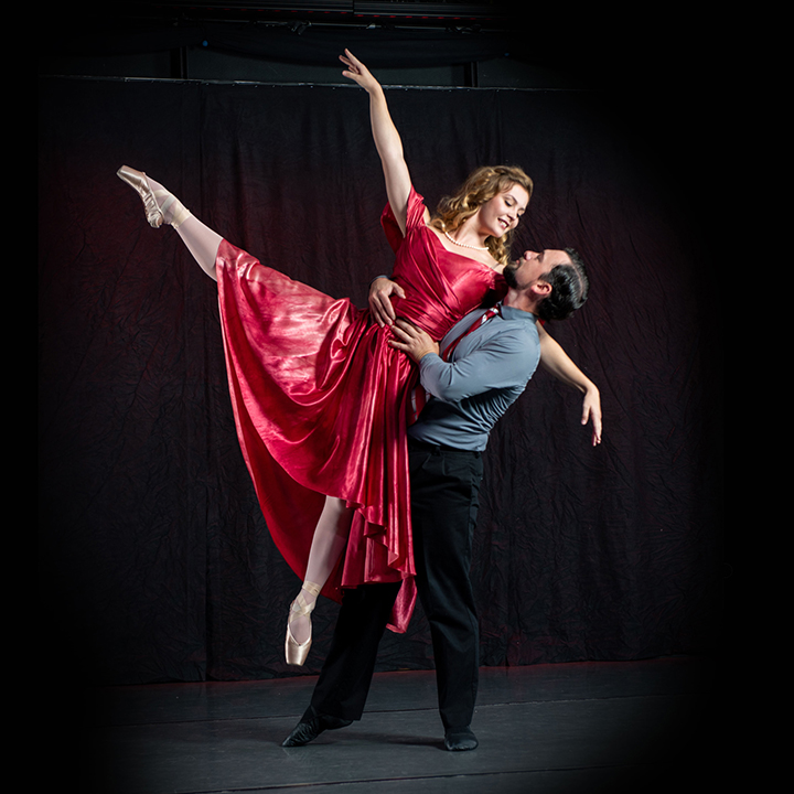A male dancer lifts a female ballet dancer.
