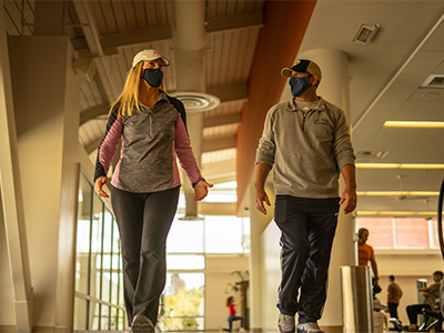 Two people walk inside the Cal Poly Recreation Center.