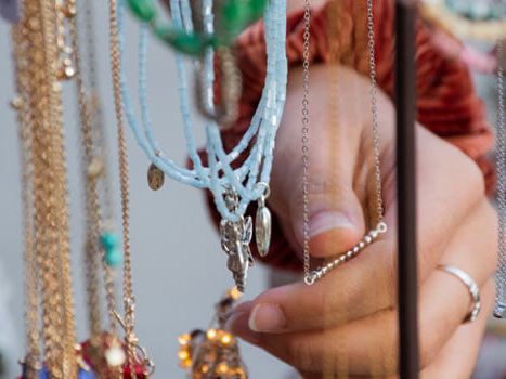 A hand touches necklaces on display