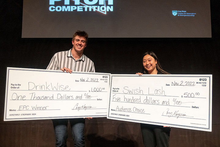 Owen Works, left, and Camille Boiteux hold signs showing the cash prizes they won at the CIE Elevator Pitch Competition