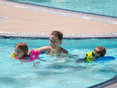 An adult and two children swim at the rec center