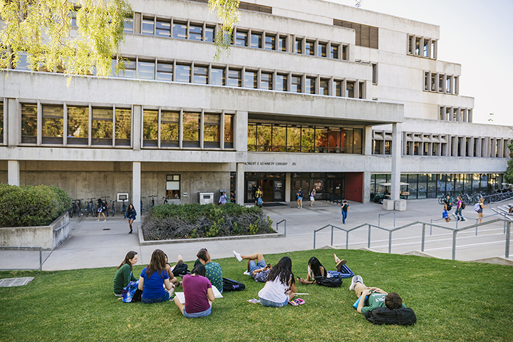 Students sit on the grass outside Kennedy Library at Cal Poly.