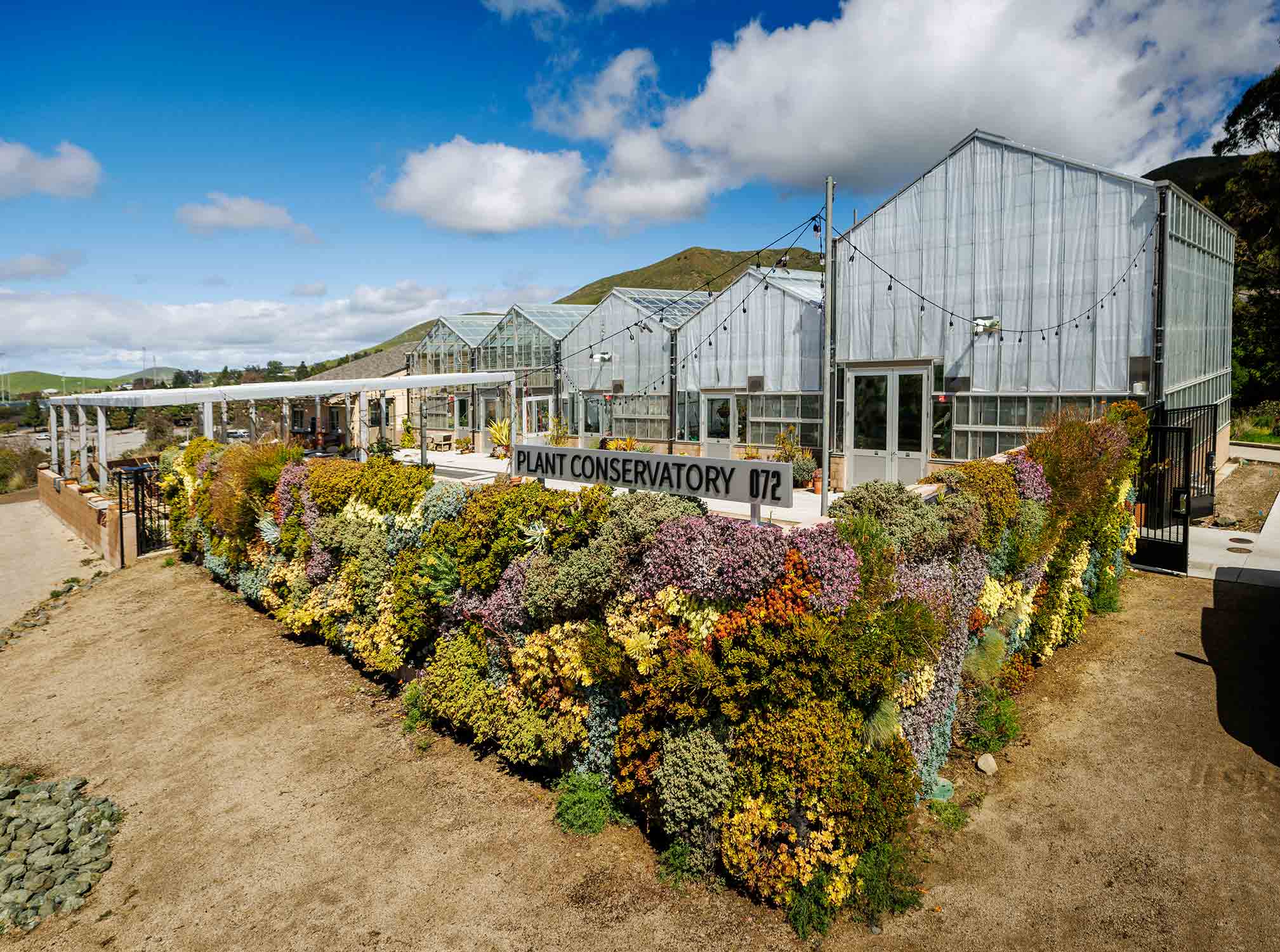 The Cal Poly Plant Conservatory building is surrounded by a living wall of flowering plants.