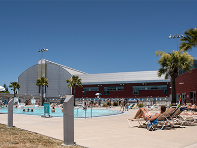 Several people relax by the pool outside the Cal Poly Recreation Center.