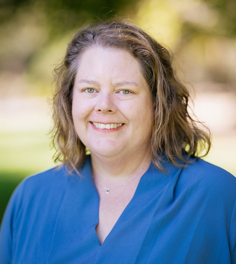A professional headshot of Professor Brenda Helmbrecht, wearing a blue shirt.
