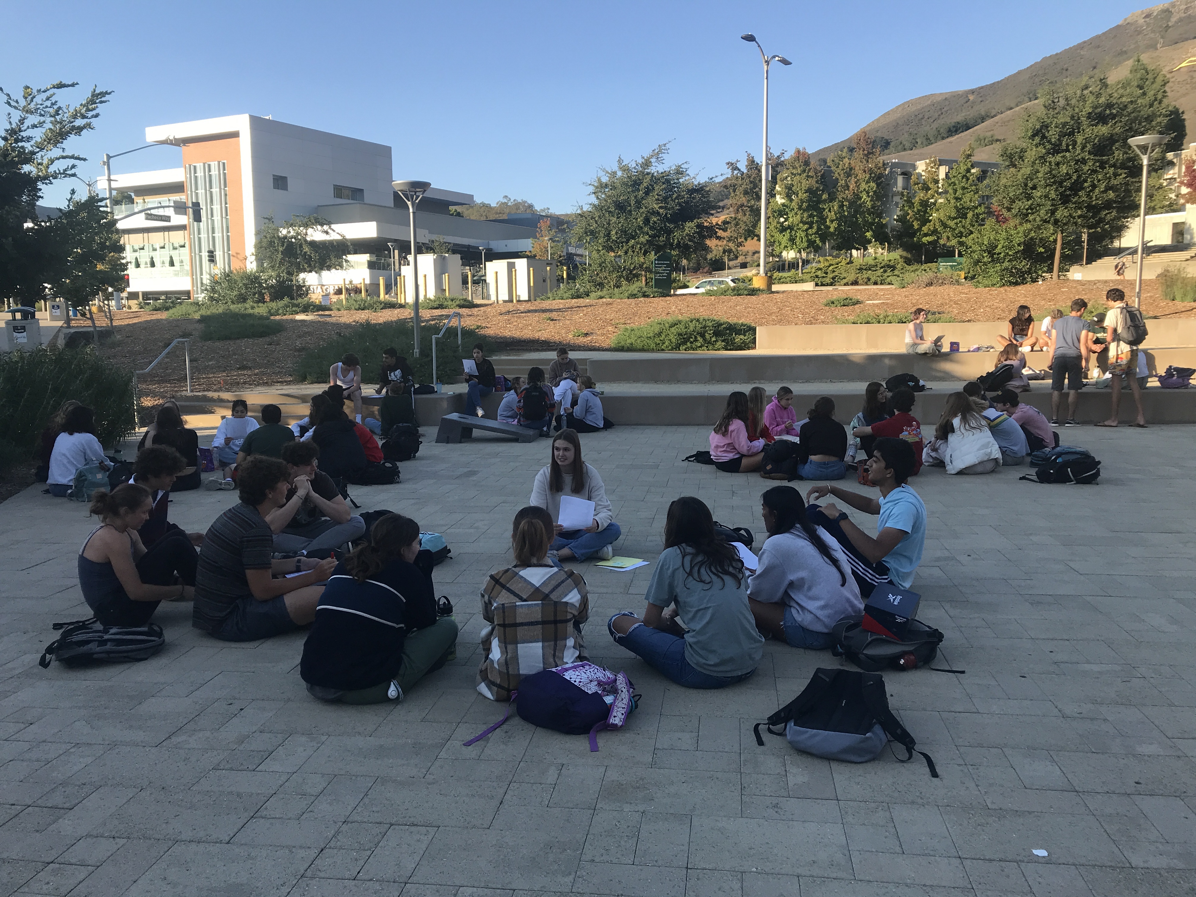 First-year honors students congregate outside on campus with their teams. 