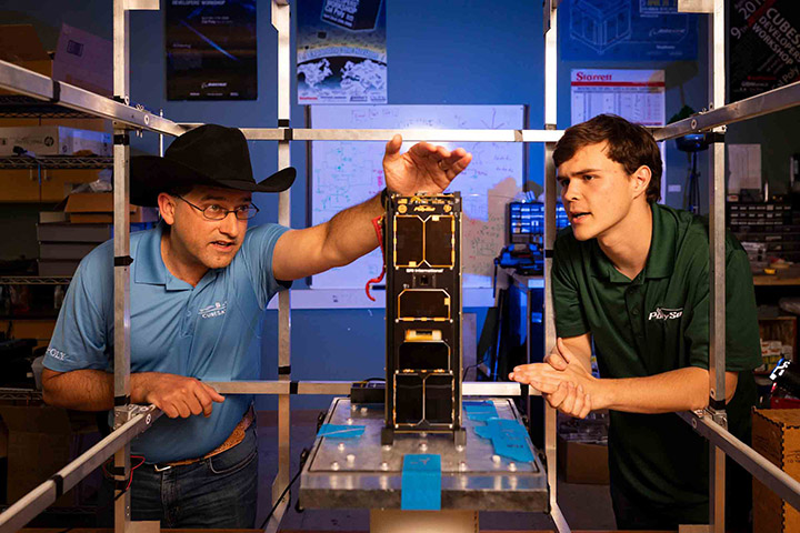 John Bellardo, left, a Cal Poly professor and advisor to the Cal Poly CubeSat program, inspects a CubeSat designed and manufactured at Cal Poly while Ryan Hunter, a computer science and mathematics major, looks on. Cal Poly’s involvement with the mini satellites has been honored with the technology’s induction into the Space Technology Hall of Fame. Credit: Joe Johnston | Cal Poly