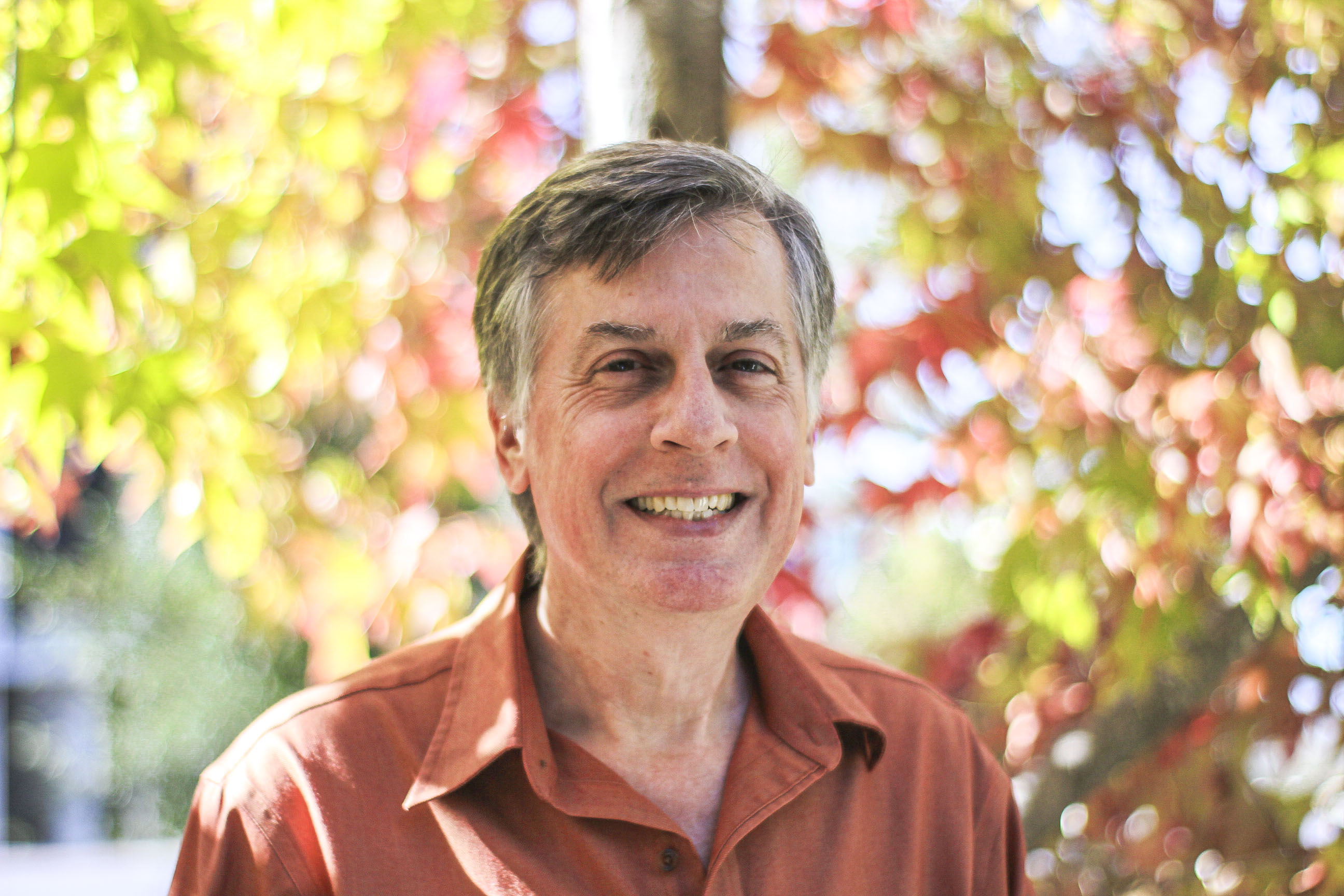 A headshot of professor Doug Keesey, pictured outside with an orange shirt on. 