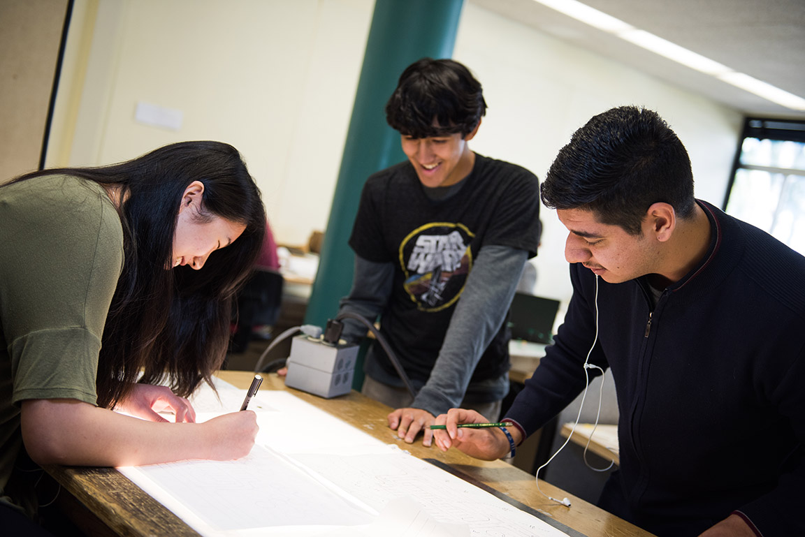 Three landscape architecture students collaborate over a light table