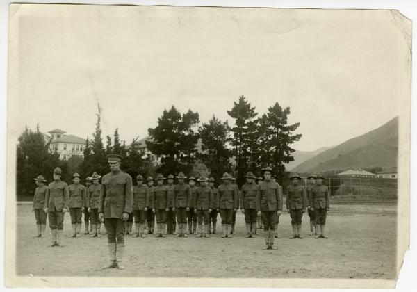A line of men in military uniform pose on campus in the 1910s.