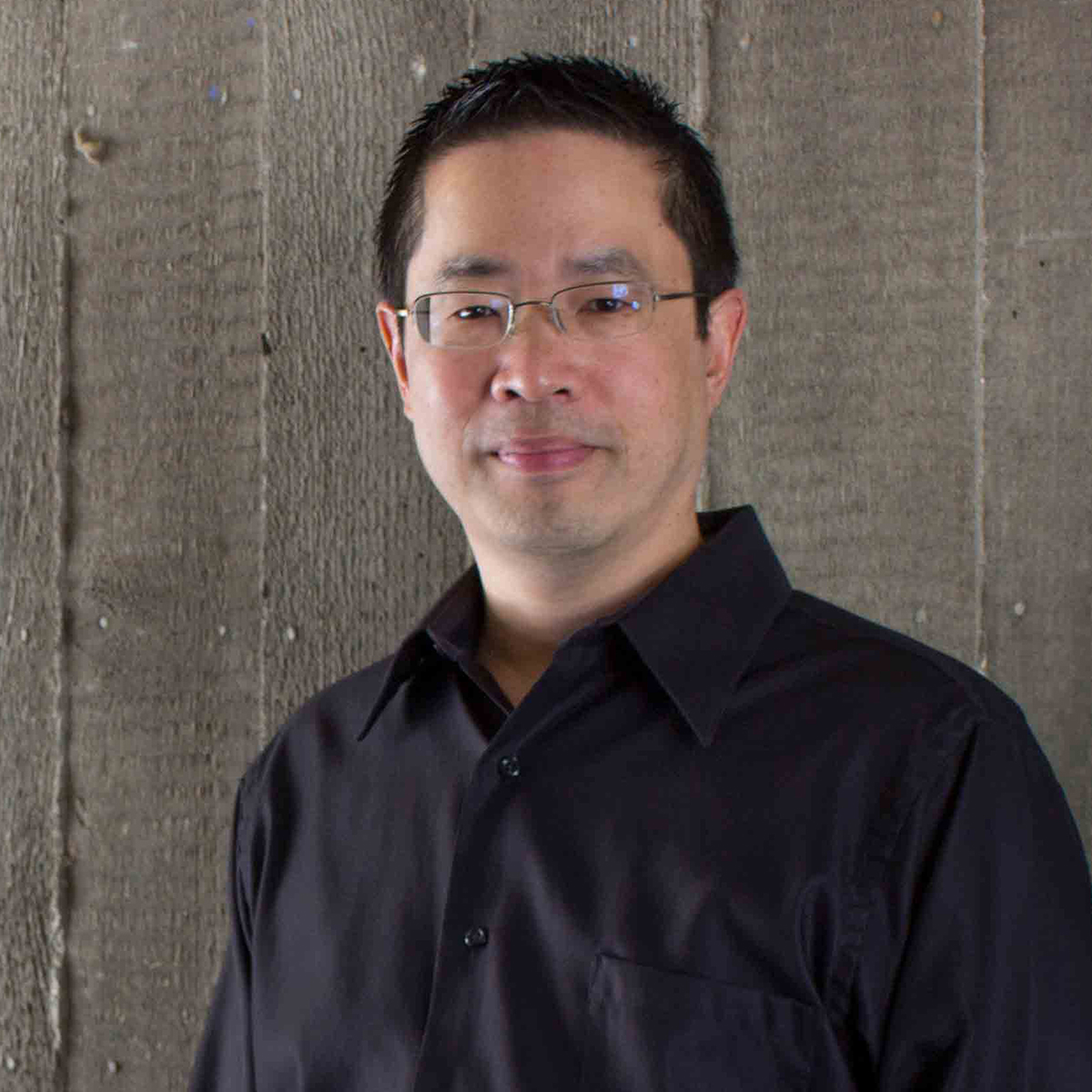 Professor Patrick Lin, wearing a black shirt in front of a grey wall