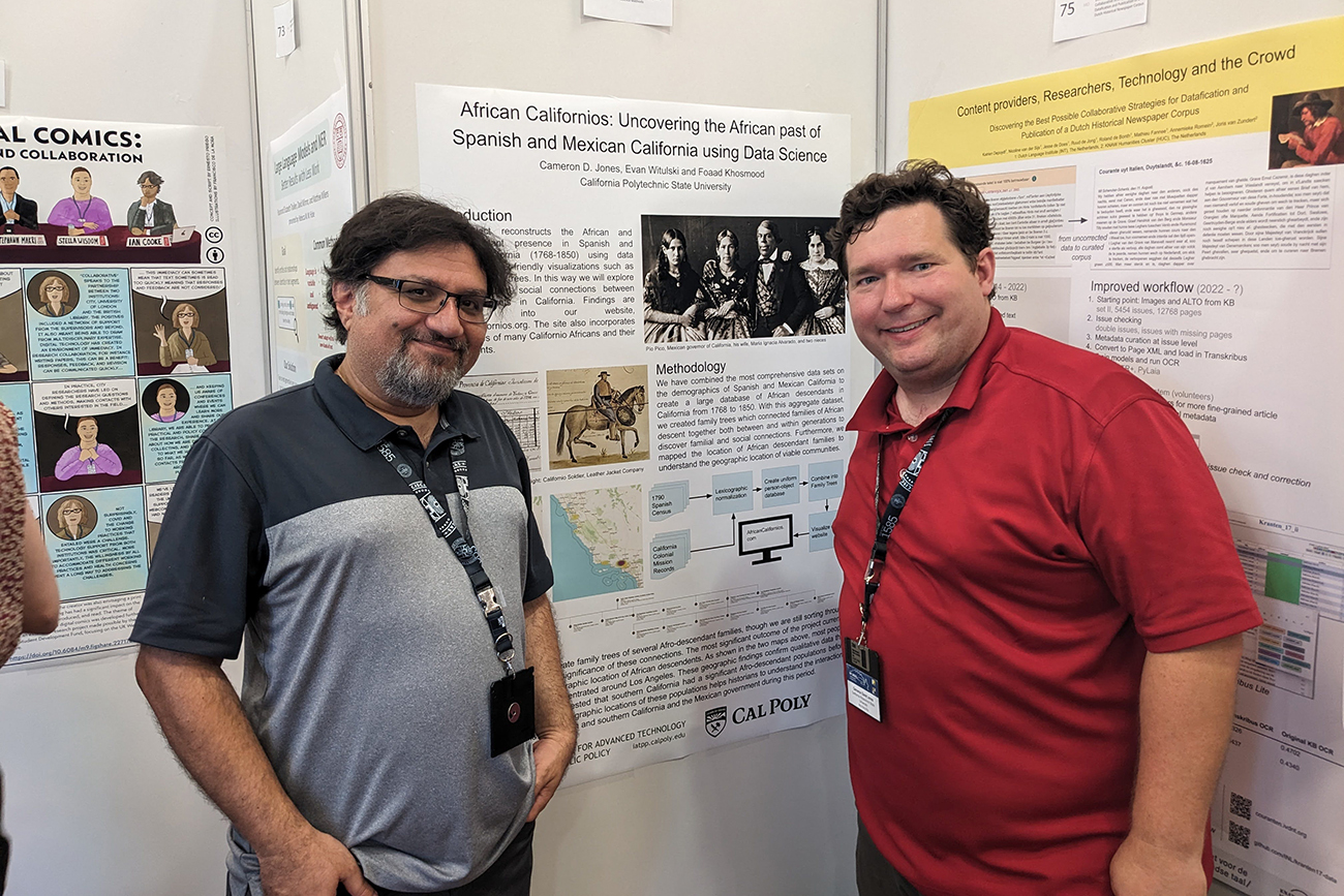 Two professors smile in front of their research poster.