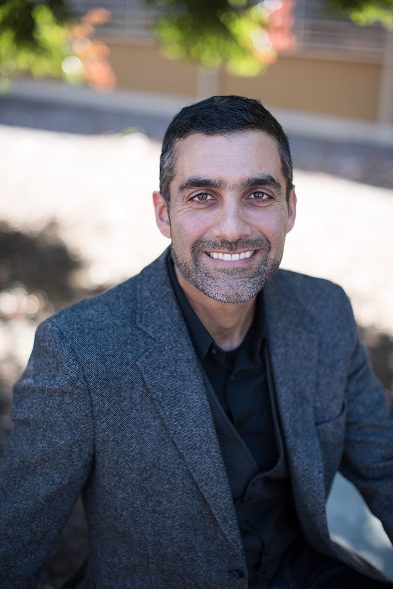 Professor Aydin Nazmi, smiling in a grey jacket