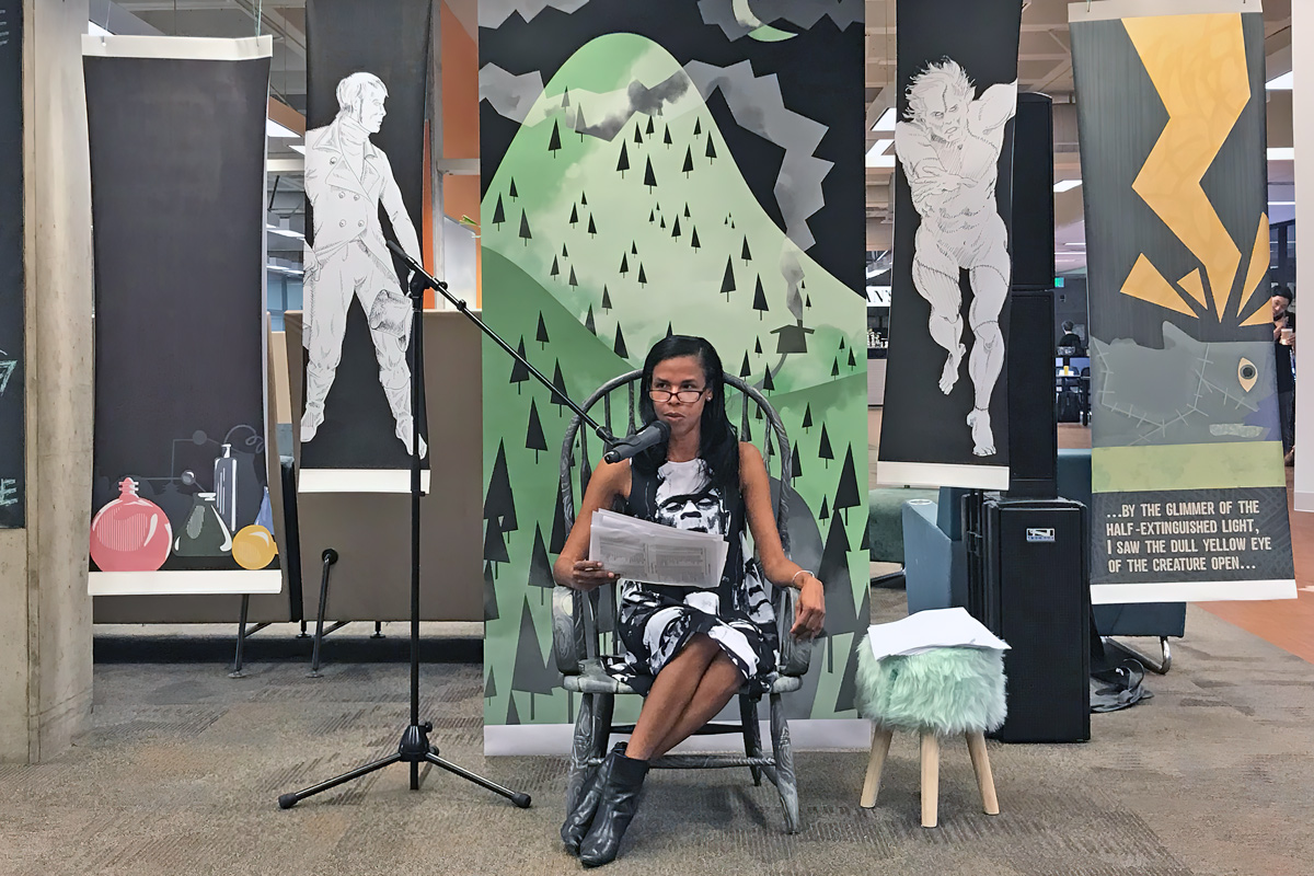Professor Regulus Allen wears a black-and-white Frankenstein dress as she sits in a chair in Kennedy Library.