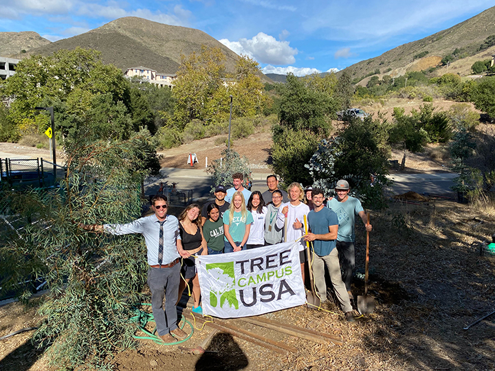 Biology Professor Matt Ritter with students holding Tree Campus USA sign on Cal Poly campus.