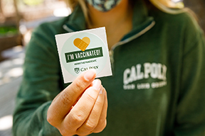 Woman holding "I'm vaccinated" sticker.