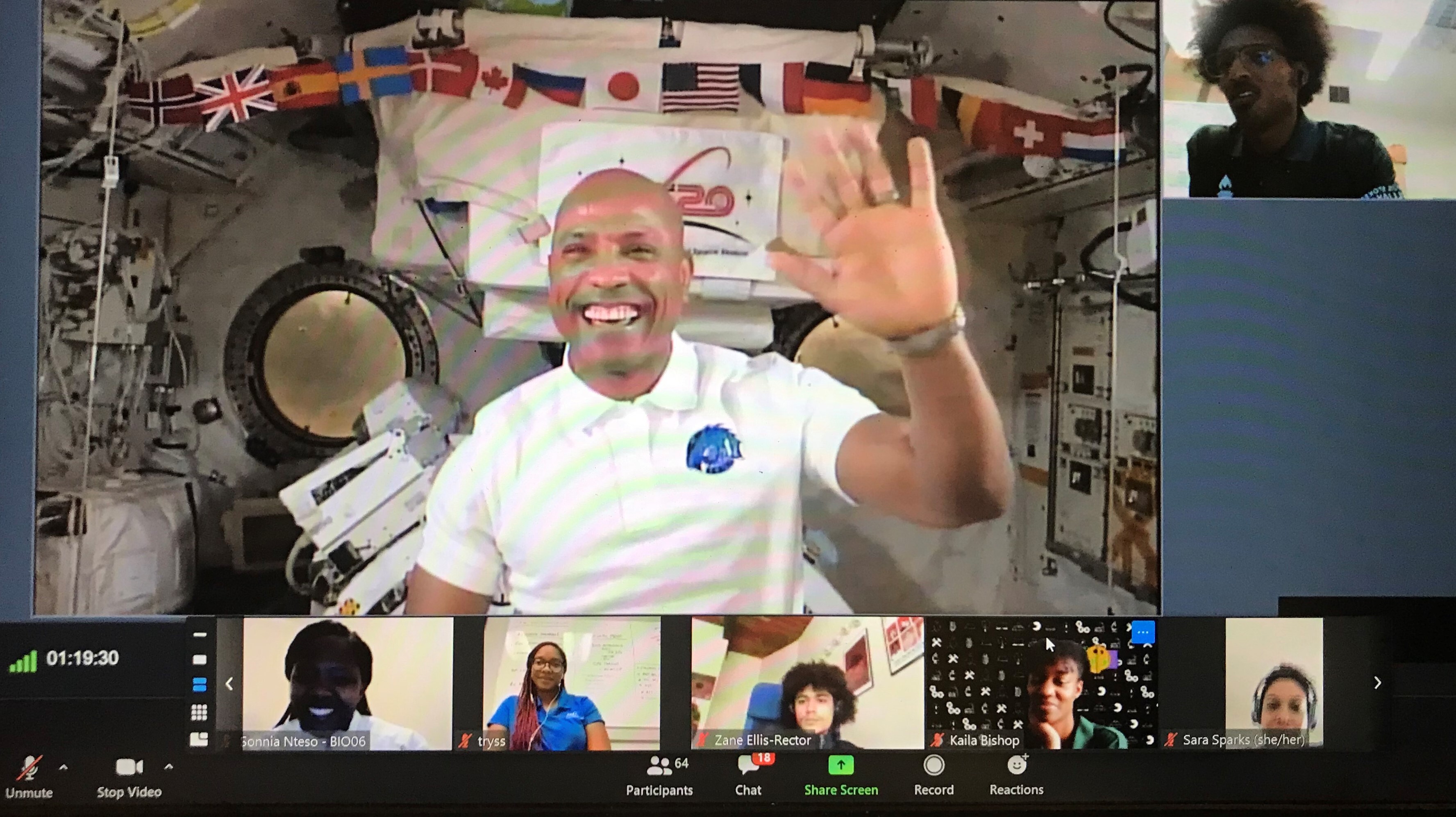 Astronaut Victor Glover smiles and waves on a Zoom call from the International Space Station