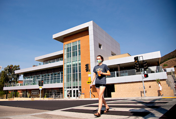 A student walks across the crosswalk in front of the Vista Grande Dining Complex
