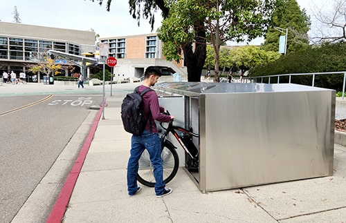 A student secures his bicycle in a lock box