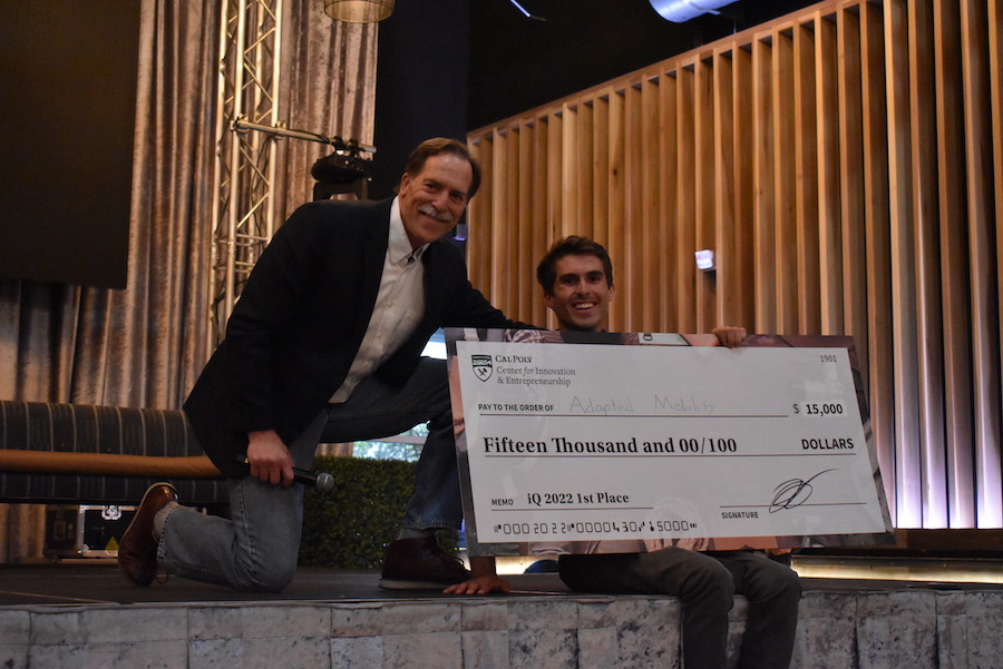 A 2022 winner of Innovation Quest poses with a large check.