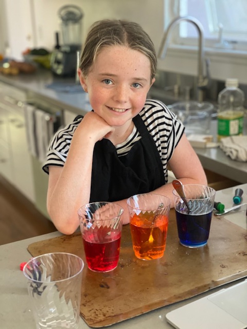Lucy Beck poses with multicolored waters during a Learn by Doing Lab experiment.